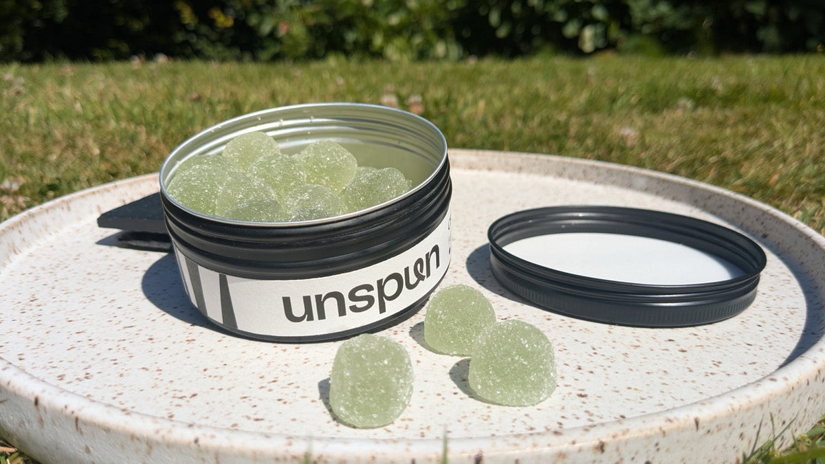 An open tin of unspun CBD gummies on a plate in a sunny garden