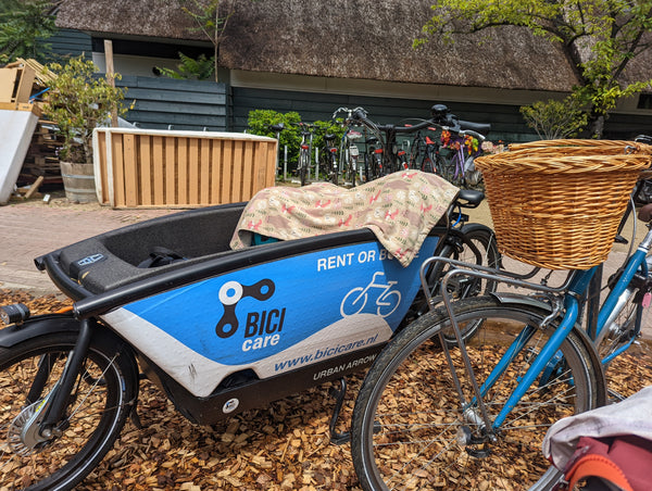 A cargo bike rented in Amsterdam, with a child's blanket draped over the front bucket