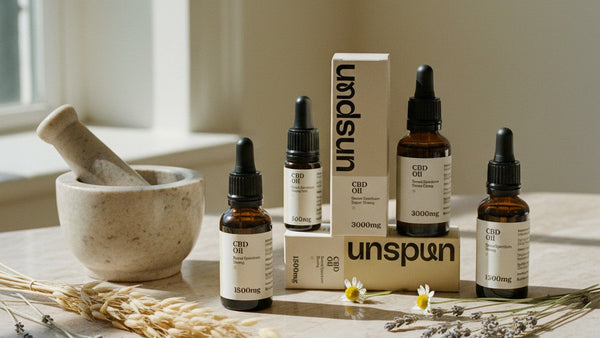 How We Make CBD Oil - Unspun oil bottles with dried botanicals