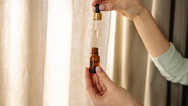 Amber glass dropper bottle held in hand with natural light
