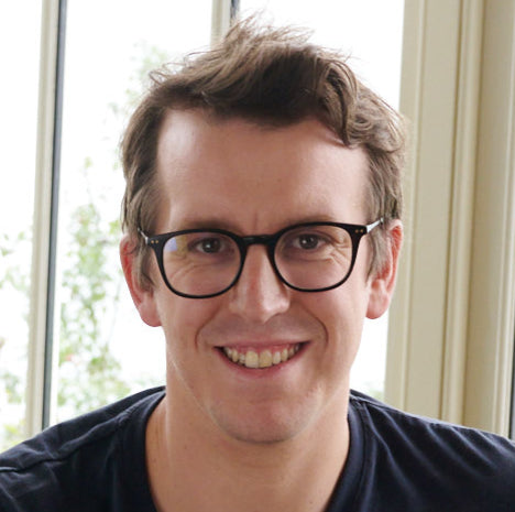 Close-up photo of Joe, co-founder of Unspun, smiling with a window behind him, reflecting the inviting and friendly ethos of the brand.