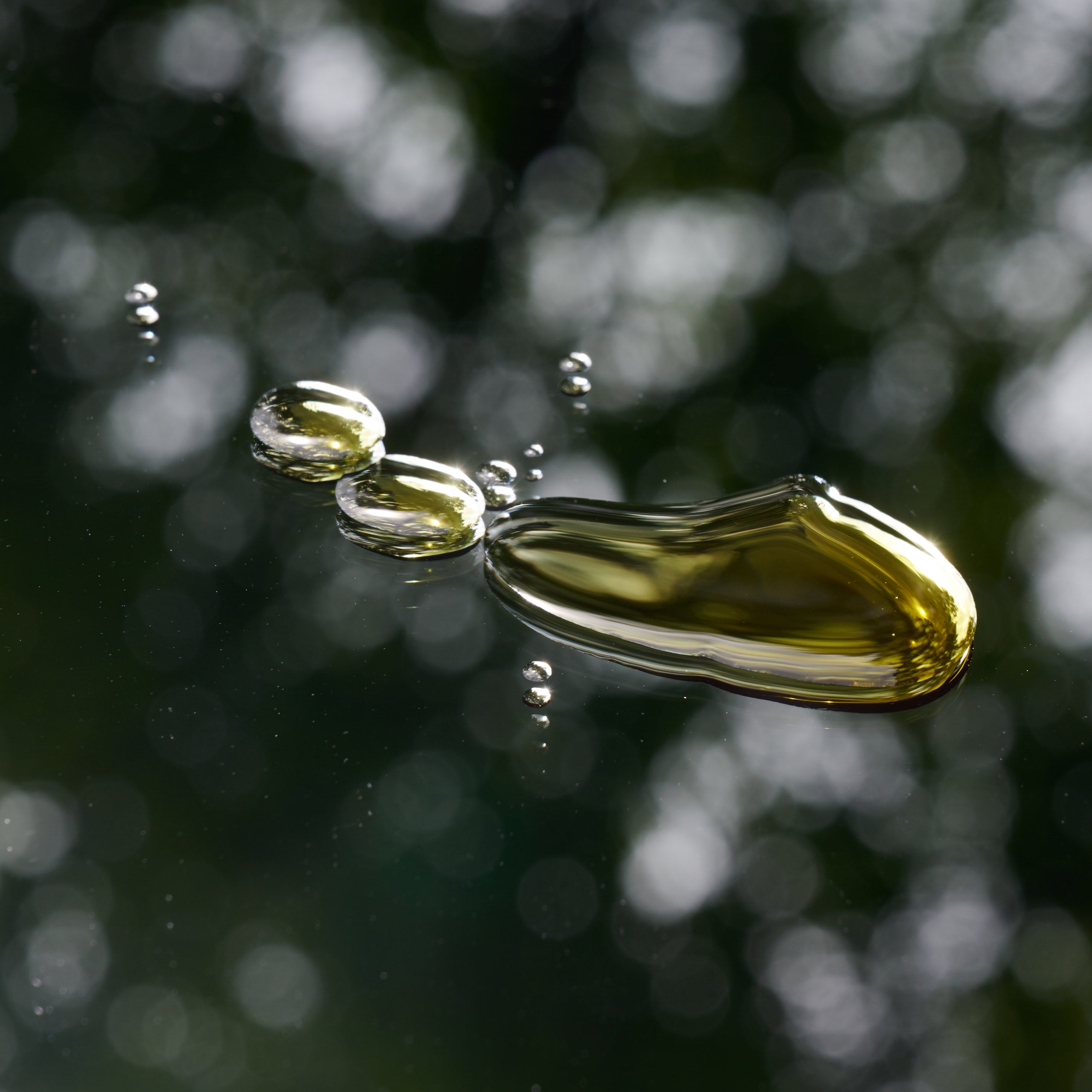 A close-up image captures golden CBD oil droplets suspended in mid-air with a blurred background of greenery, reflecting the product's natural essence and purity.